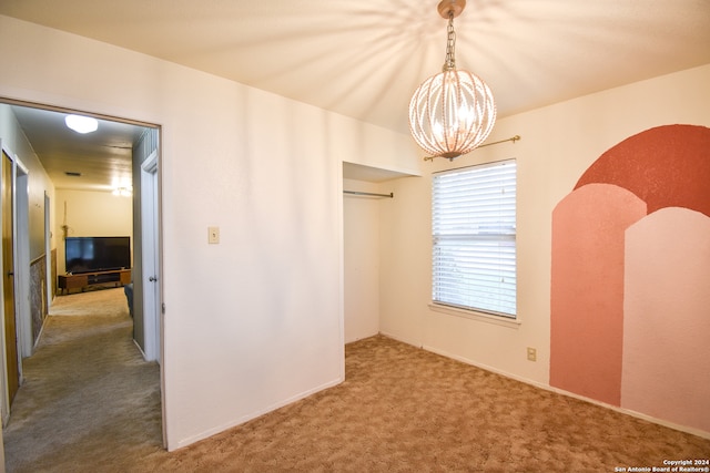 unfurnished bedroom featuring a chandelier and dark carpet