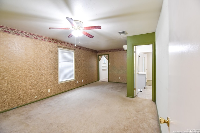 unfurnished bedroom with ceiling fan, connected bathroom, and light tile flooring