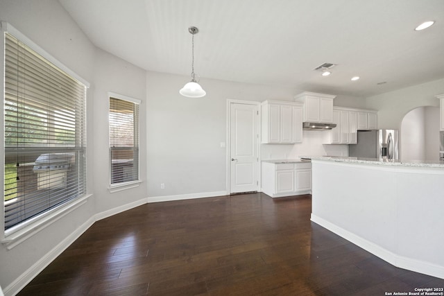 kitchen with light stone counters, decorative light fixtures, dark hardwood / wood-style flooring, stainless steel refrigerator with ice dispenser, and white cabinets