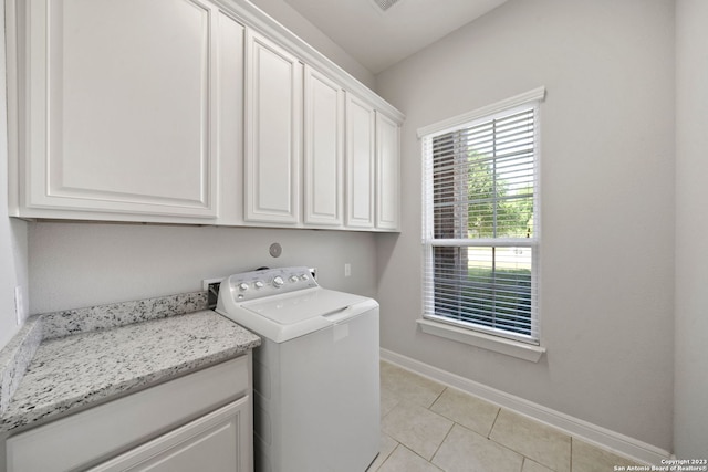 clothes washing area with cabinets, light tile flooring, and washer / dryer