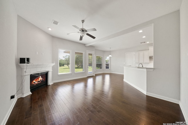 unfurnished living room featuring dark wood-type flooring, ceiling fan, and sink