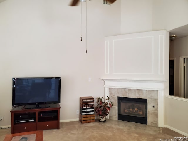 living area with baseboards, a tiled fireplace, a ceiling fan, and light colored carpet