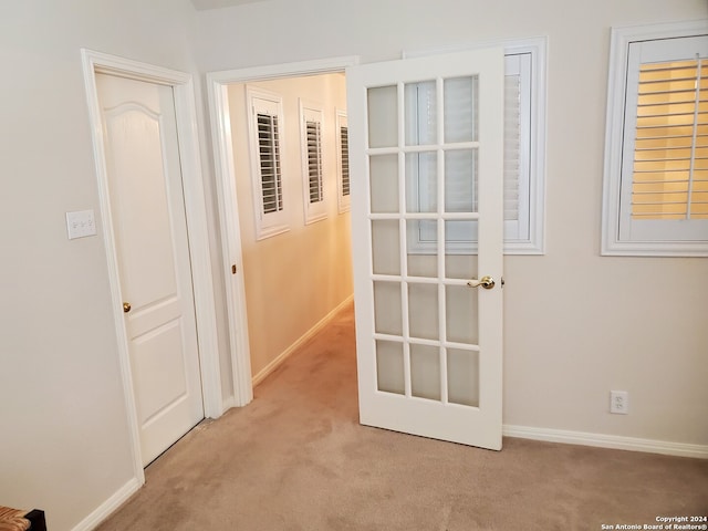 hall featuring light carpet and baseboards