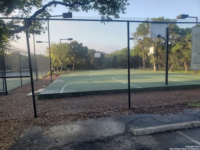 view of basketball court featuring a healthy amount of sunlight, community basketball court, and fence