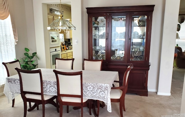 carpeted dining space with an inviting chandelier