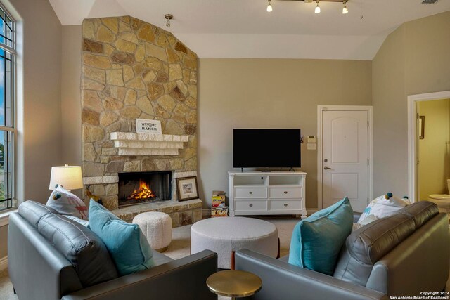 carpeted living room with plenty of natural light, lofted ceiling, track lighting, and a fireplace