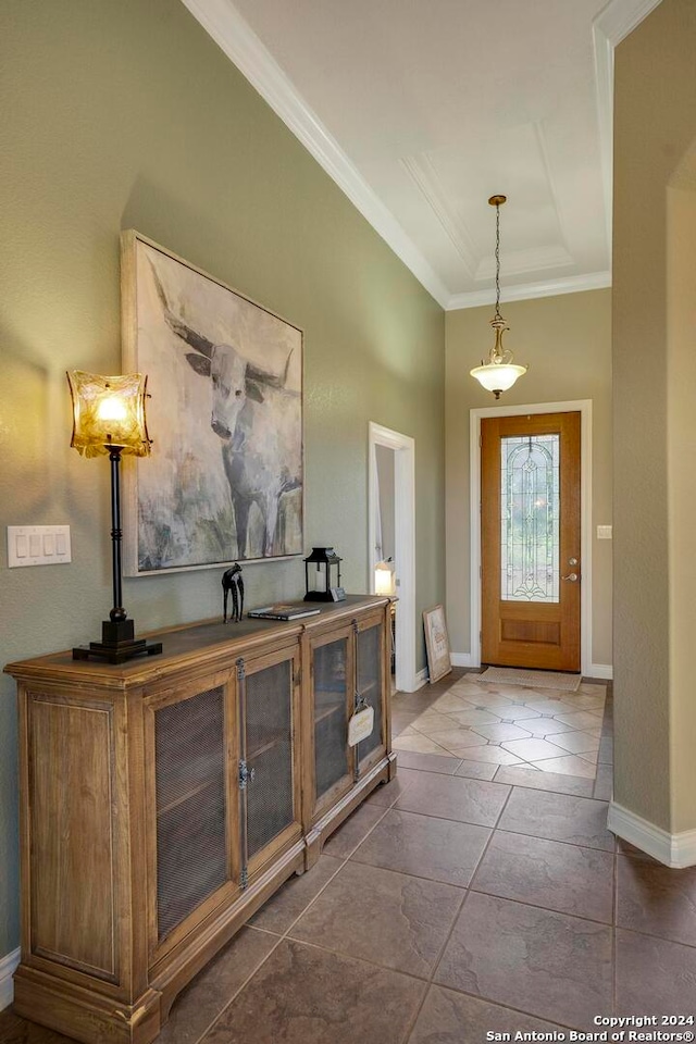 entryway with ornamental molding and dark tile floors