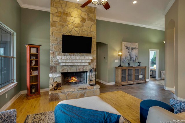 living room featuring ornamental molding, a fireplace, ceiling fan, and light tile floors