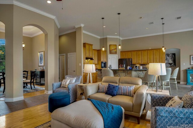 tiled living room featuring ornamental molding and a towering ceiling