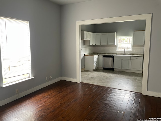 kitchen with sink, white cabinets, stainless steel dishwasher, tasteful backsplash, and dark hardwood / wood-style flooring