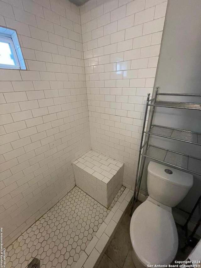 bathroom with toilet, tile flooring, and tiled shower