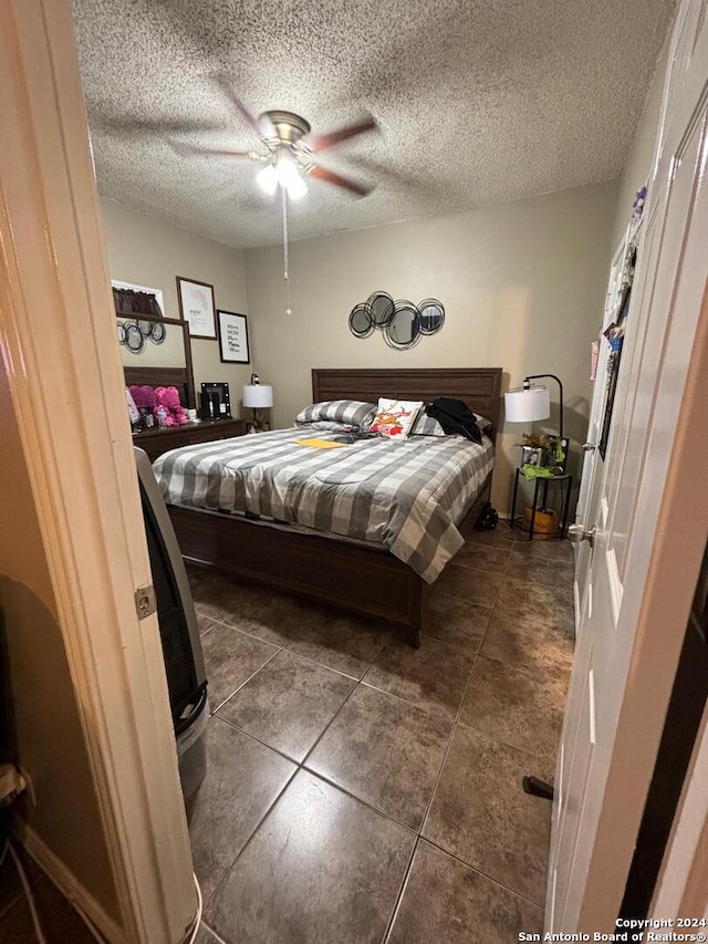 tiled bedroom featuring a textured ceiling and ceiling fan