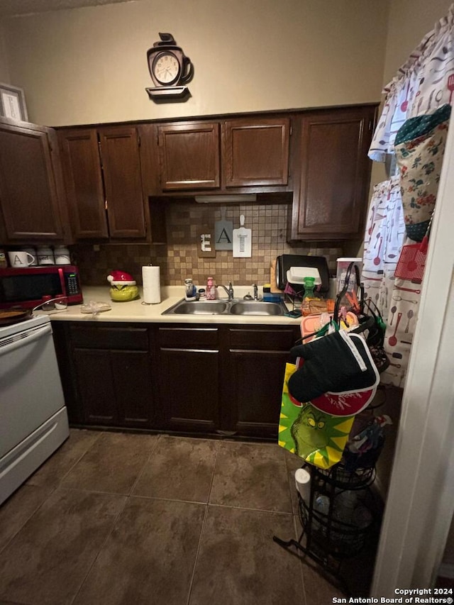 kitchen with dark tile flooring, tasteful backsplash, sink, and dark brown cabinetry