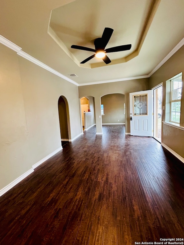 unfurnished living room with ceiling fan, crown molding, dark hardwood / wood-style floors, and a tray ceiling