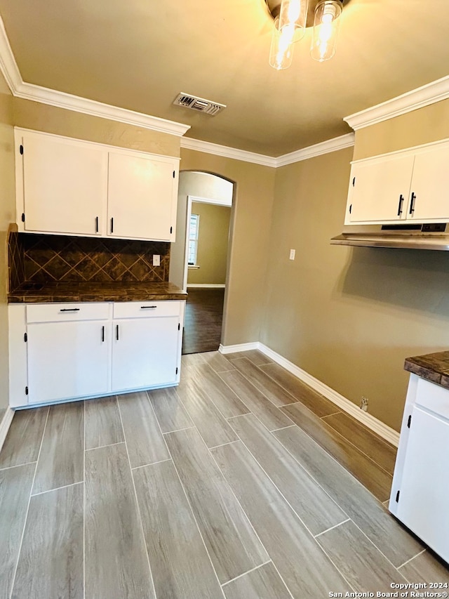 kitchen with white cabinetry, backsplash, and light hardwood / wood-style flooring