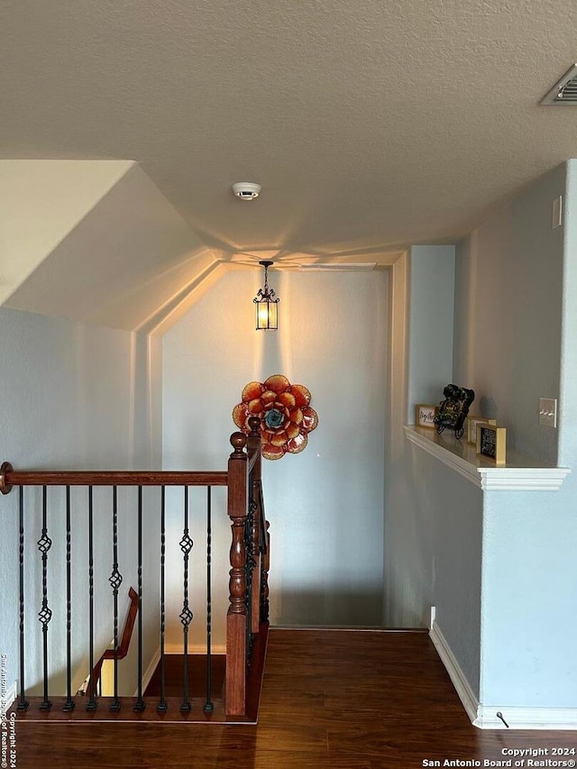 stairs with dark hardwood / wood-style floors, a textured ceiling, and lofted ceiling