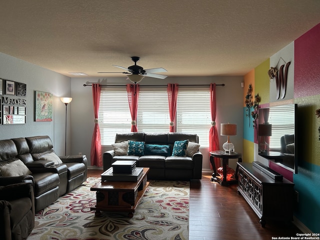 living room featuring a textured ceiling, ceiling fan, and dark wood-type flooring