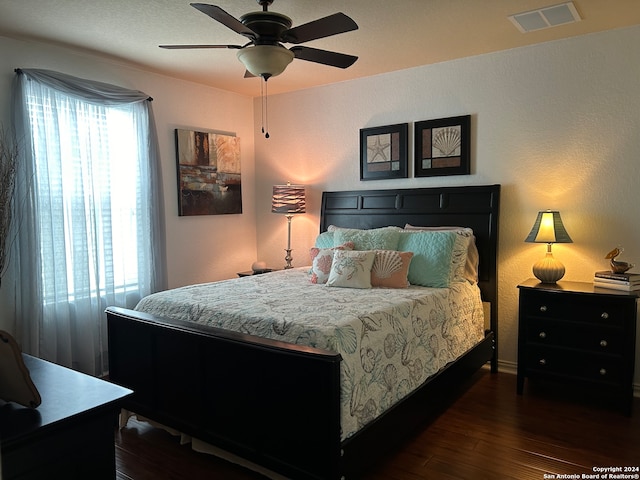 bedroom with dark wood-type flooring, multiple windows, and ceiling fan