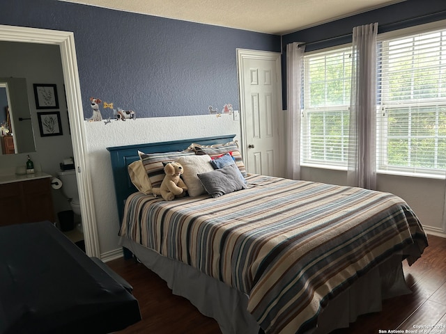 bedroom with multiple windows and dark hardwood / wood-style flooring