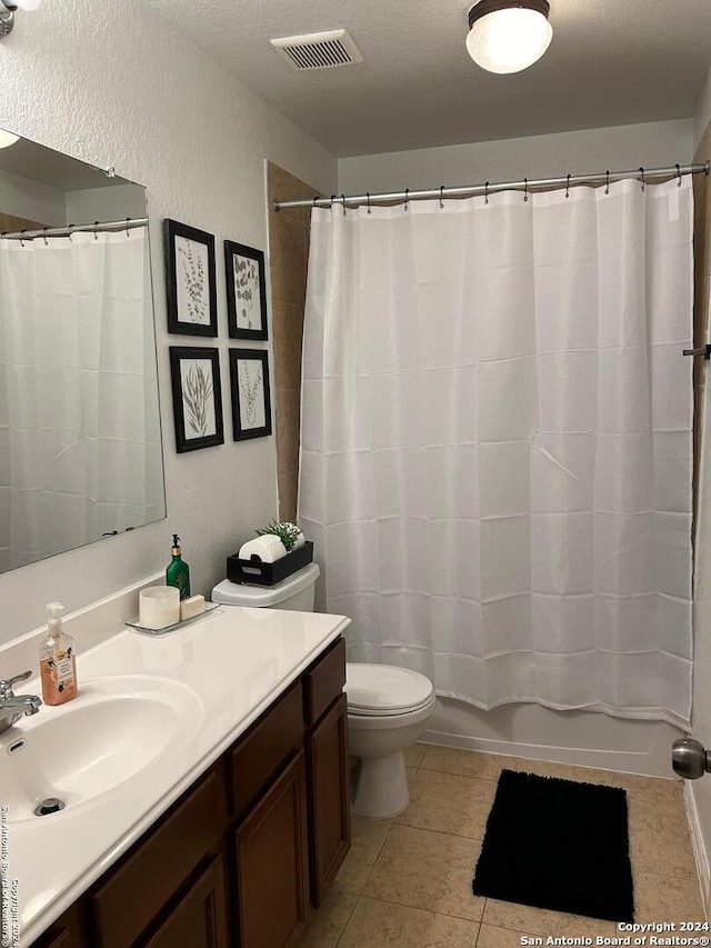 bathroom featuring toilet, tile floors, large vanity, and a textured ceiling