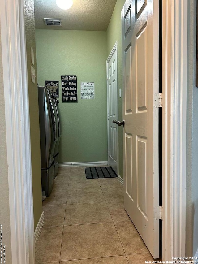 interior space featuring light tile floors, washing machine and dryer, and a textured ceiling