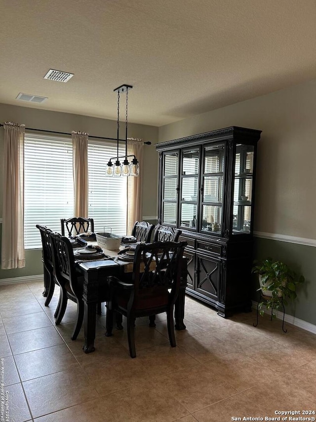 dining area featuring an inviting chandelier, a textured ceiling, and light tile flooring