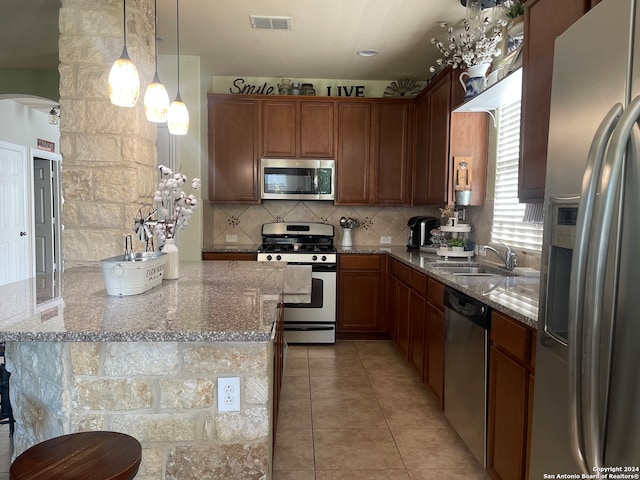 kitchen with appliances with stainless steel finishes, light stone counters, tasteful backsplash, pendant lighting, and sink