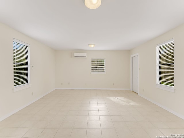 tiled empty room featuring an AC wall unit and plenty of natural light