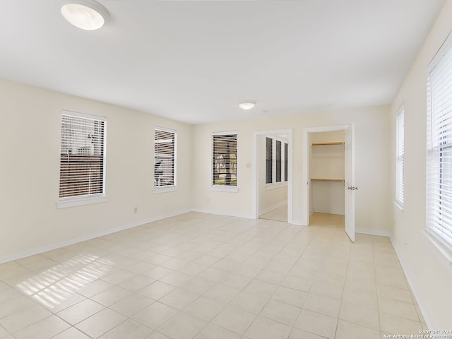 unfurnished bedroom with a closet, a walk in closet, and light tile floors