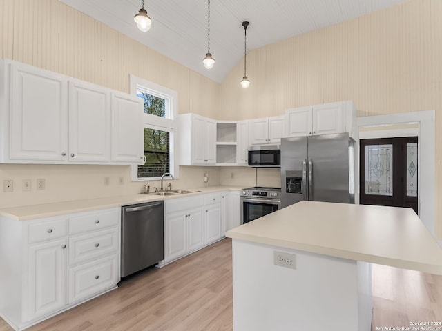 kitchen with sink, white cabinets, stainless steel appliances, decorative light fixtures, and light wood-type flooring