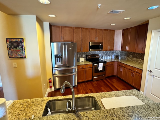 kitchen with sink, dark hardwood / wood-style flooring, backsplash, stainless steel appliances, and light stone countertops