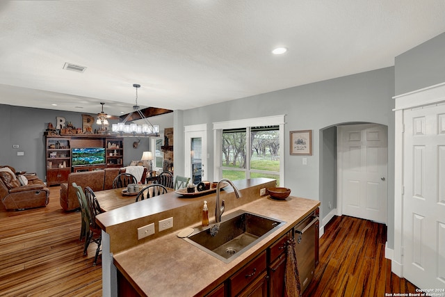 kitchen featuring dark wood-type flooring, ceiling fan, a textured ceiling, decorative light fixtures, and sink