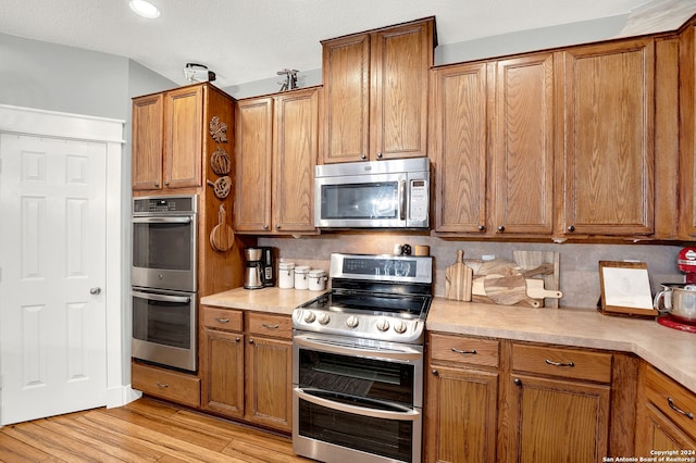 kitchen featuring backsplash, light hardwood / wood-style flooring, and appliances with stainless steel finishes