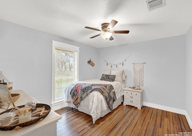 bedroom with ceiling fan, a textured ceiling, and dark wood-type flooring