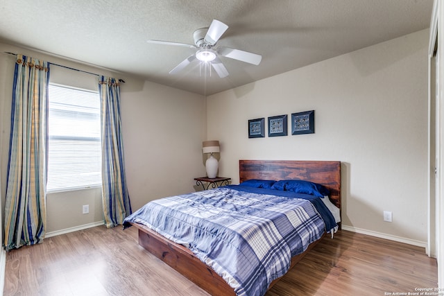 bedroom featuring ceiling fan, light hardwood / wood-style flooring, and a textured ceiling