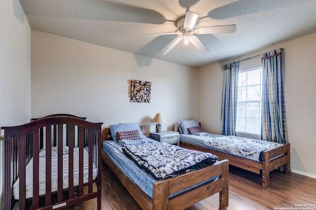 bedroom featuring ceiling fan, a textured ceiling, and dark wood-type flooring