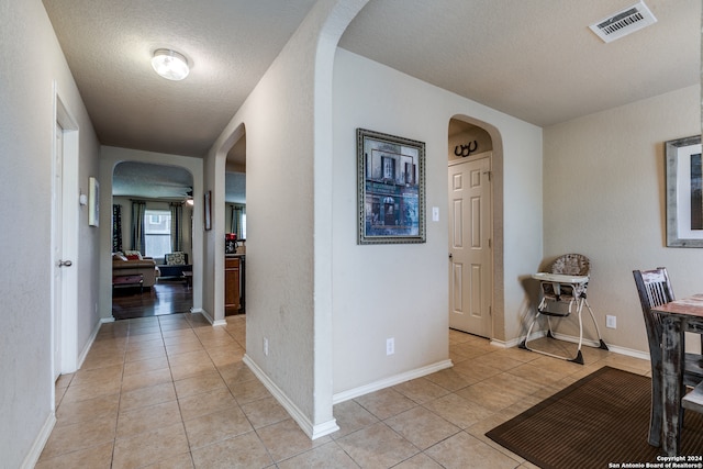 interior space with a textured ceiling and light tile floors