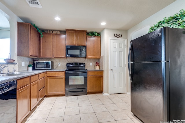 kitchen with backsplash, sink, light tile floors, and black appliances