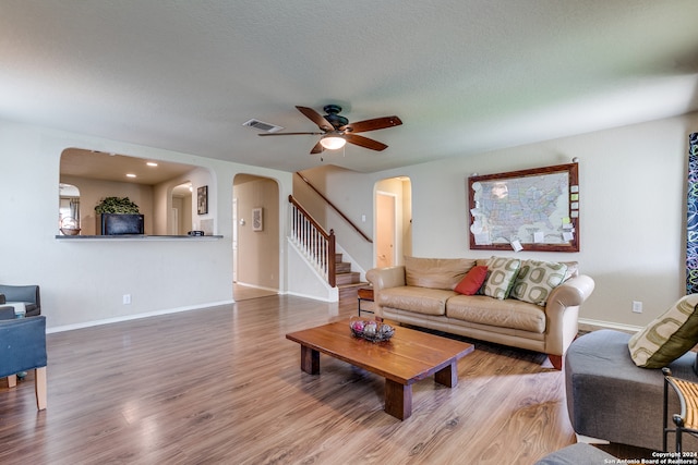 living room featuring a textured ceiling, light hardwood / wood-style floors, and ceiling fan