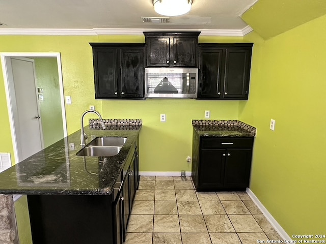 kitchen with light tile flooring, sink, dark stone counters, and kitchen peninsula