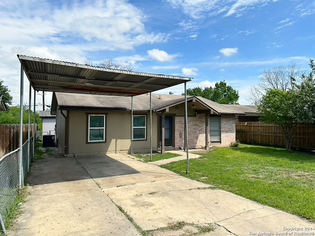 rear view of property with a lawn and a carport