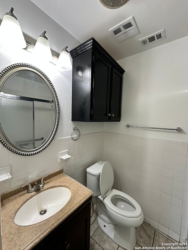 bathroom with toilet, large vanity, tile walls, backsplash, and tile floors