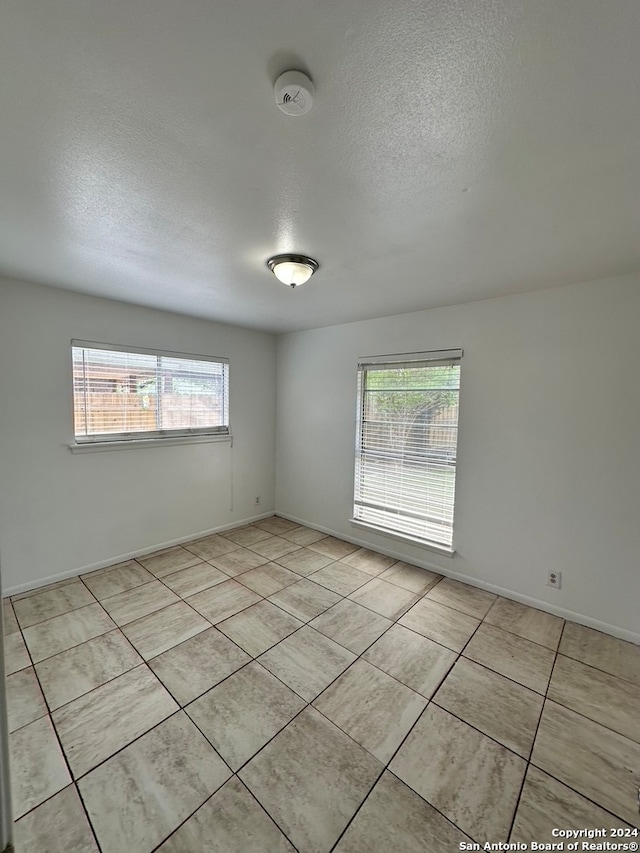 tiled spare room with plenty of natural light and a textured ceiling