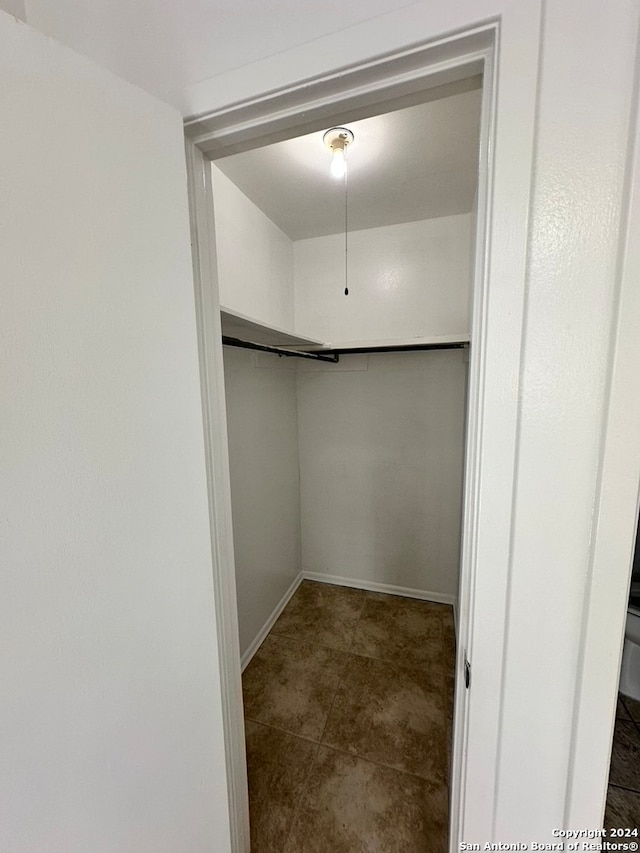 walk in closet with dark tile flooring