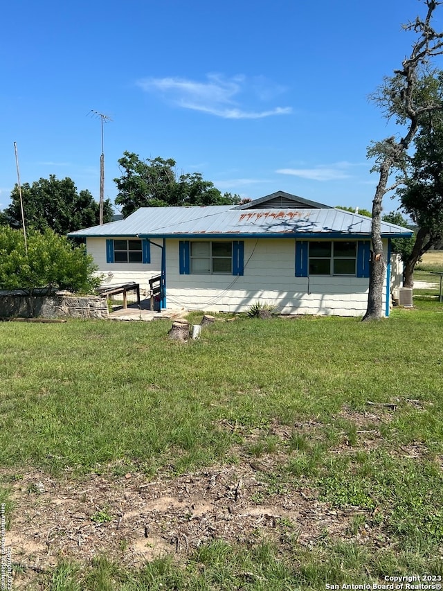 rear view of property with a lawn and central air condition unit