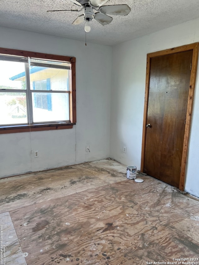 empty room with ceiling fan and a textured ceiling