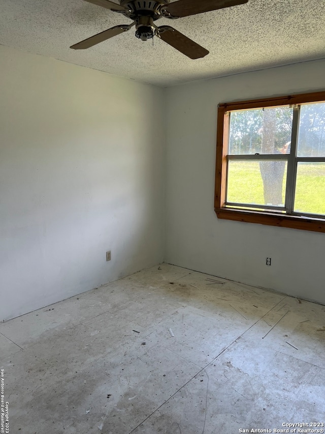 empty room with ceiling fan and a textured ceiling