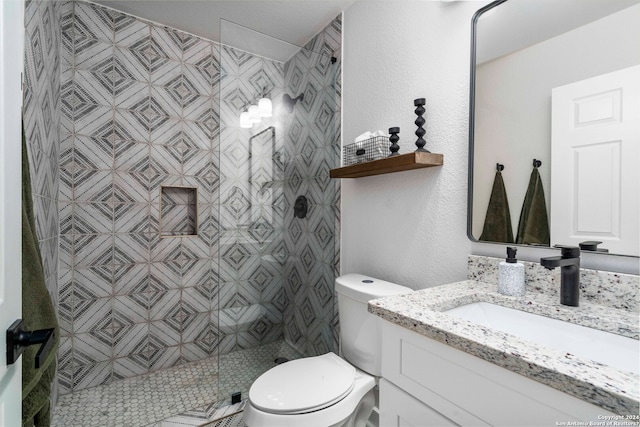 bathroom featuring toilet, a tile shower, and vanity with extensive cabinet space