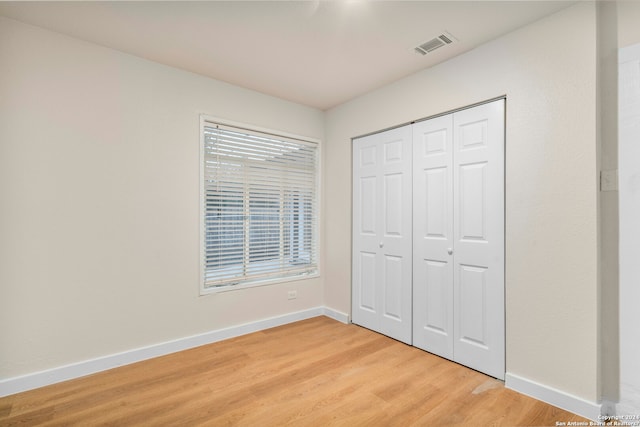 unfurnished bedroom with a closet and light hardwood / wood-style floors