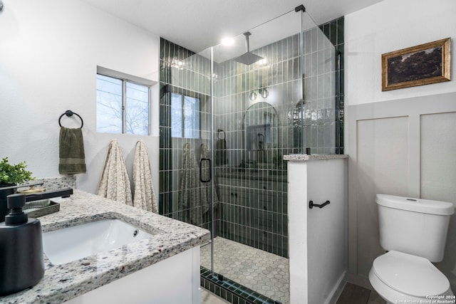 bathroom featuring tile floors, a shower with door, toilet, and vanity